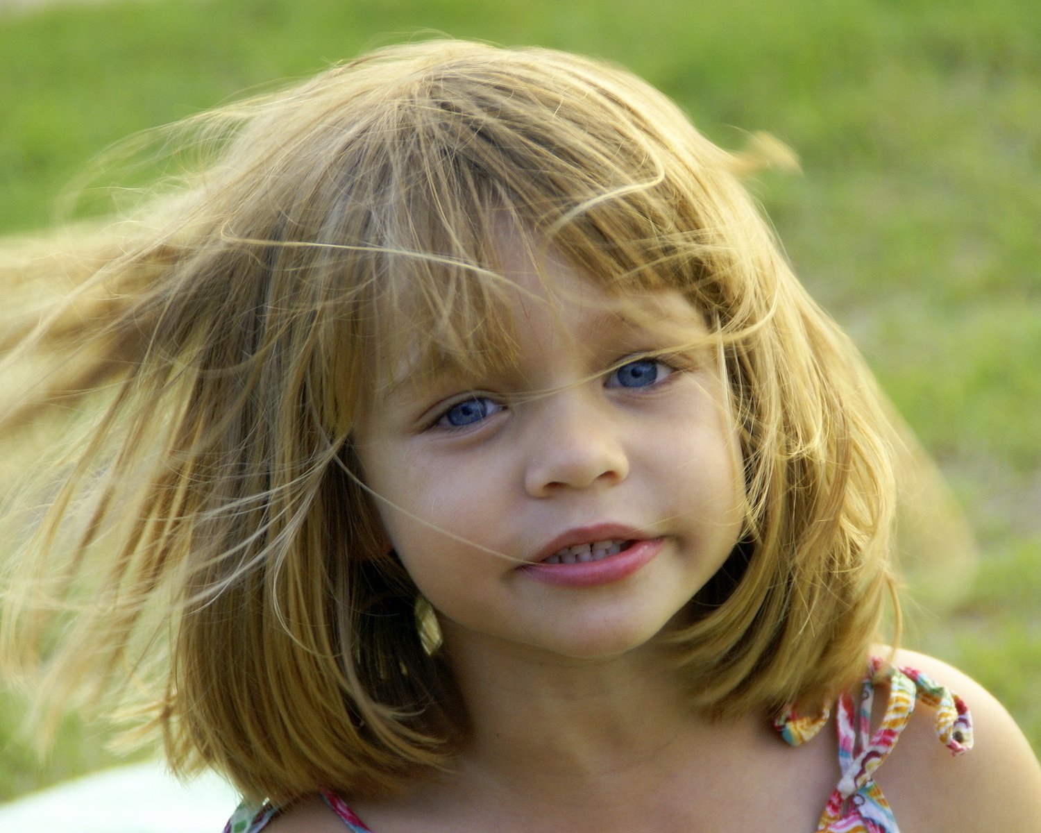 a child with a hairdo stands in front of the camera