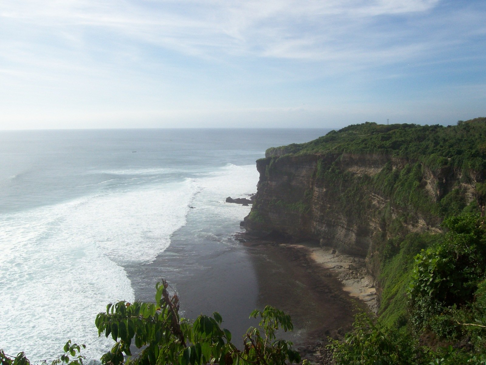 a large cliff at the end of a very steep beach