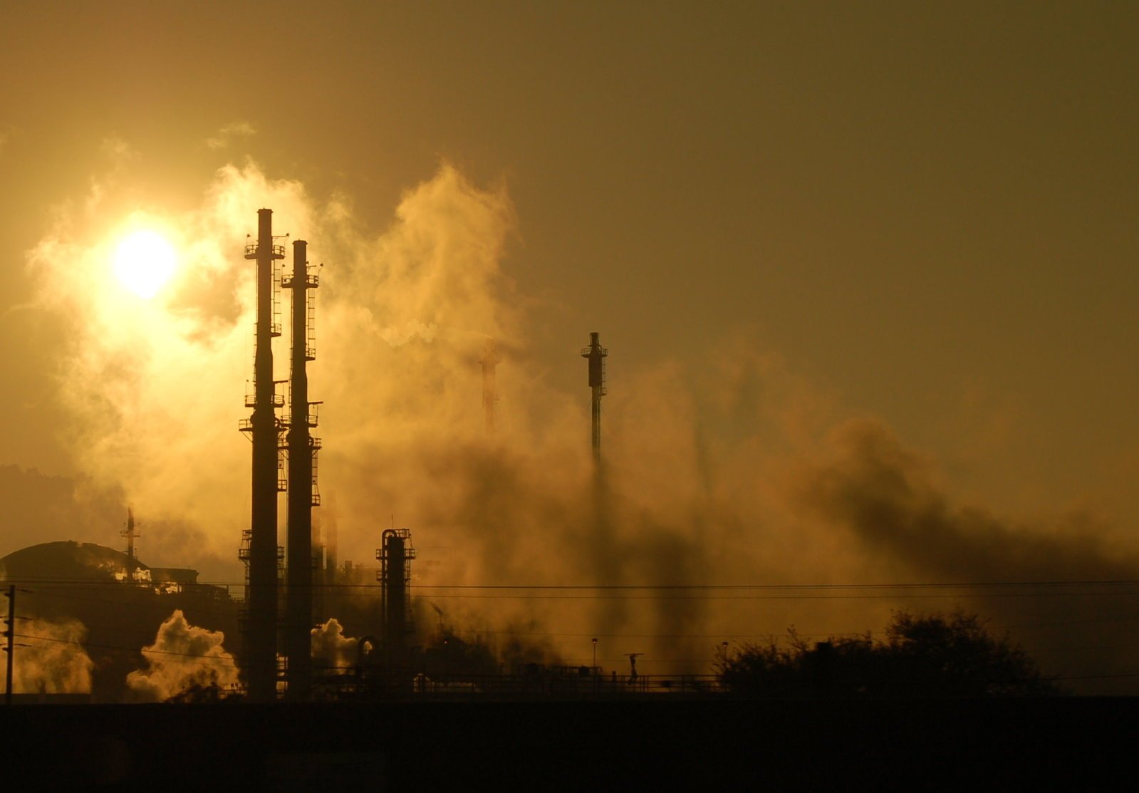 smokestacks and pipes against a setting sun