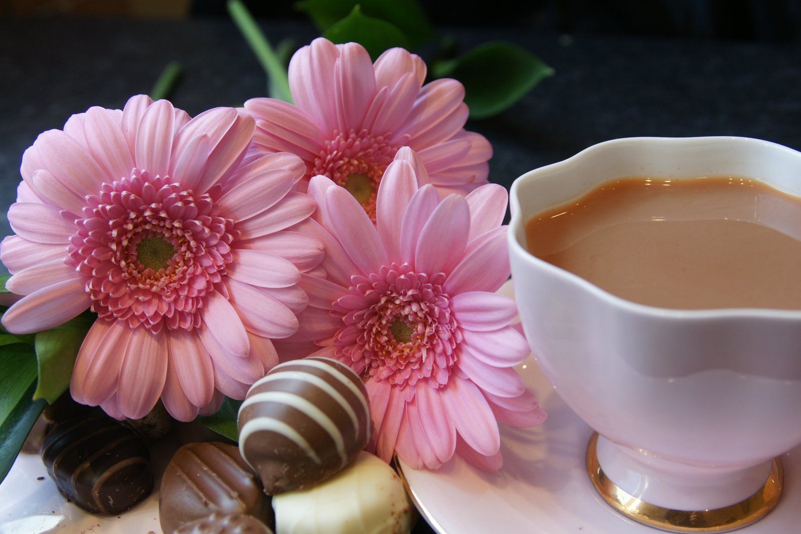a coffee and chocolate set with flowers in the background