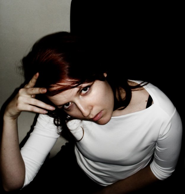 a woman in a white shirt sitting in the dark