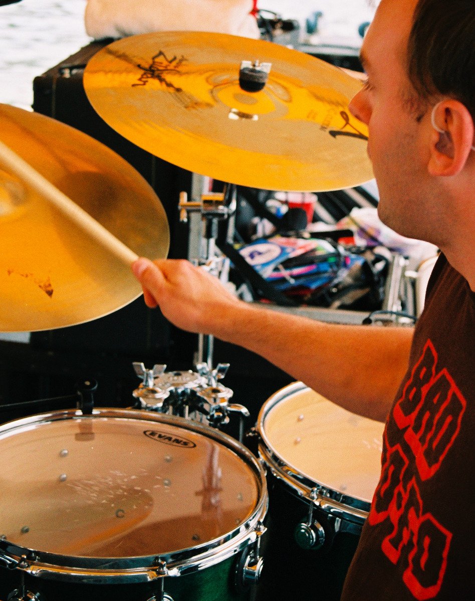 a man holding a sticks while behind him drum set