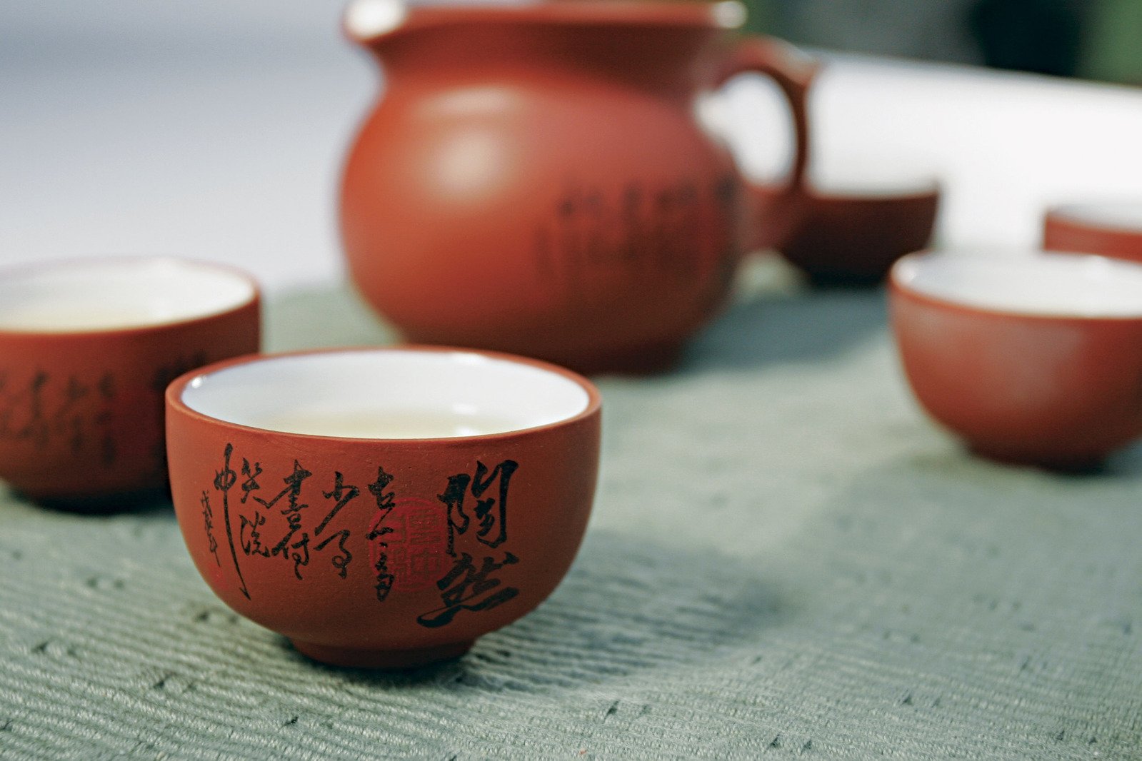 four cups and a pitcher on a cloth