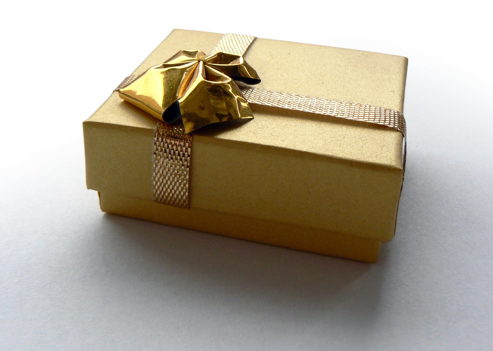 a gold gift wrapped with a bow and decorated with ribbons