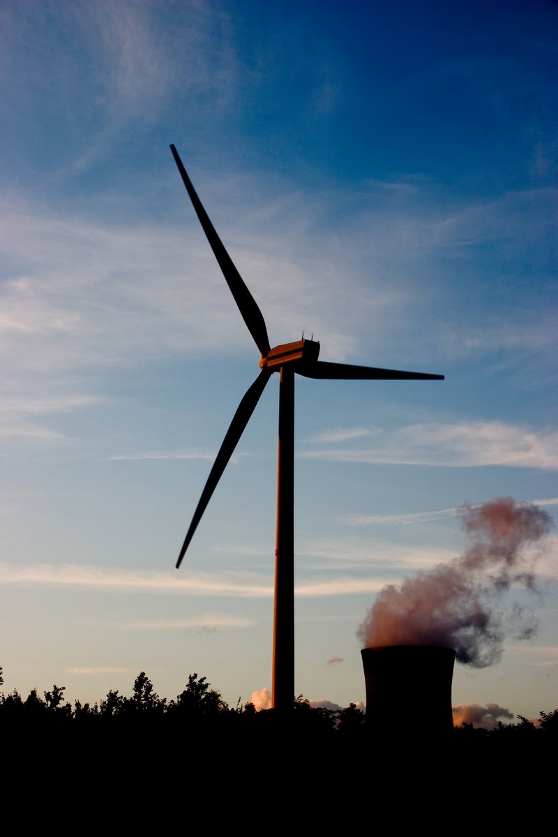 there is a pipe near a windmill with smoke coming out