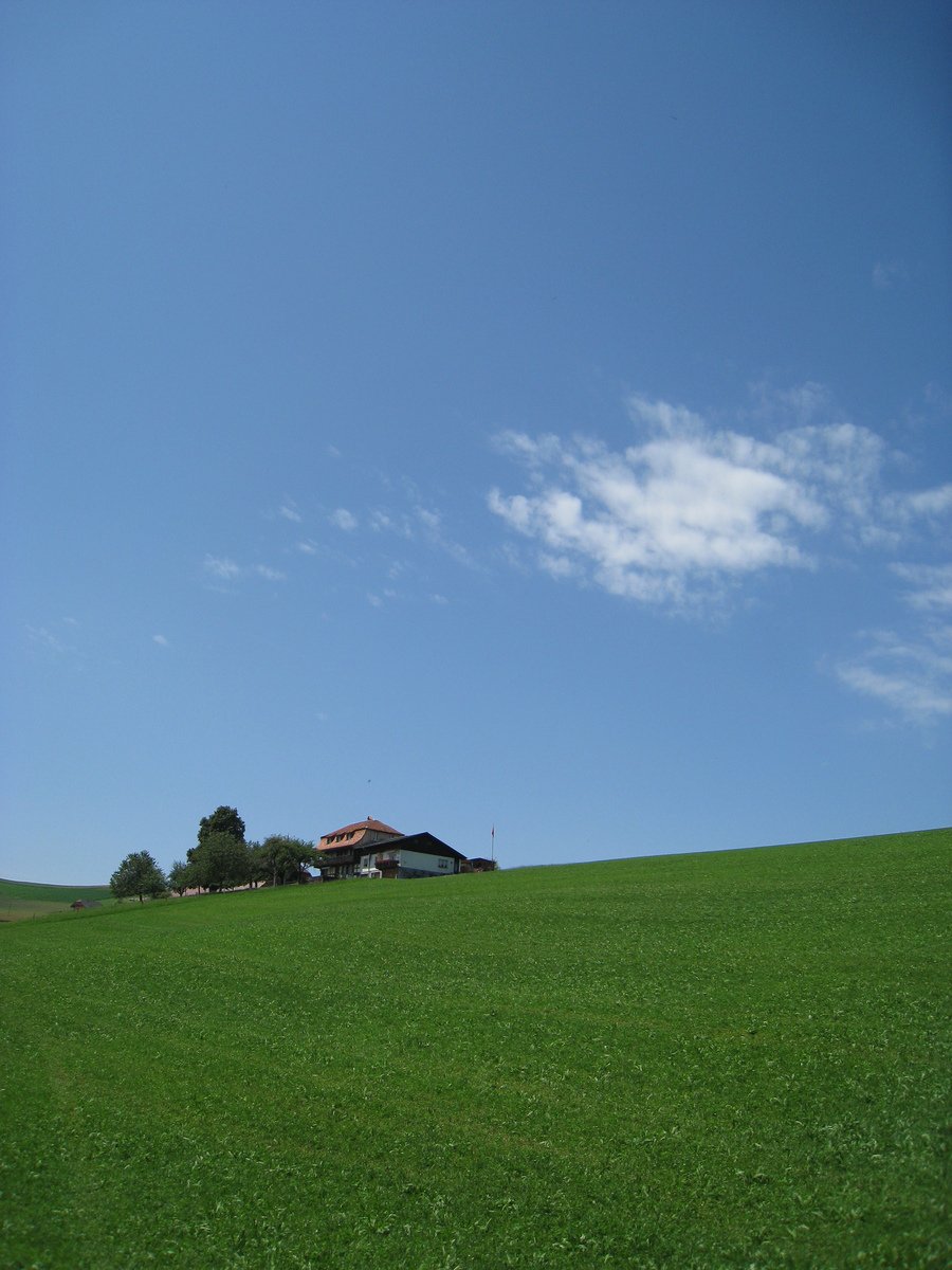 a building in the distance on top of a large green hill