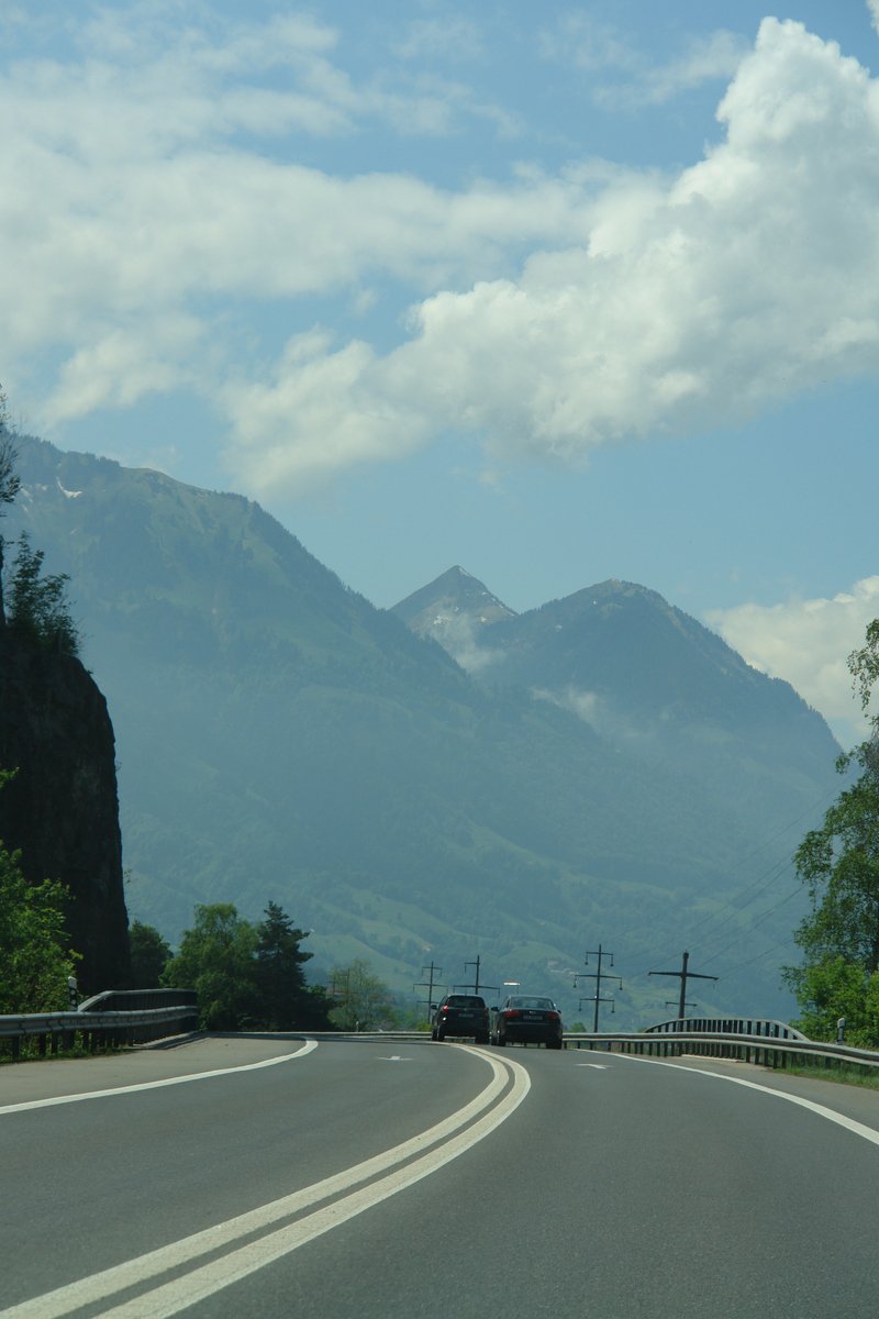 a car driving down the road toward the mountains