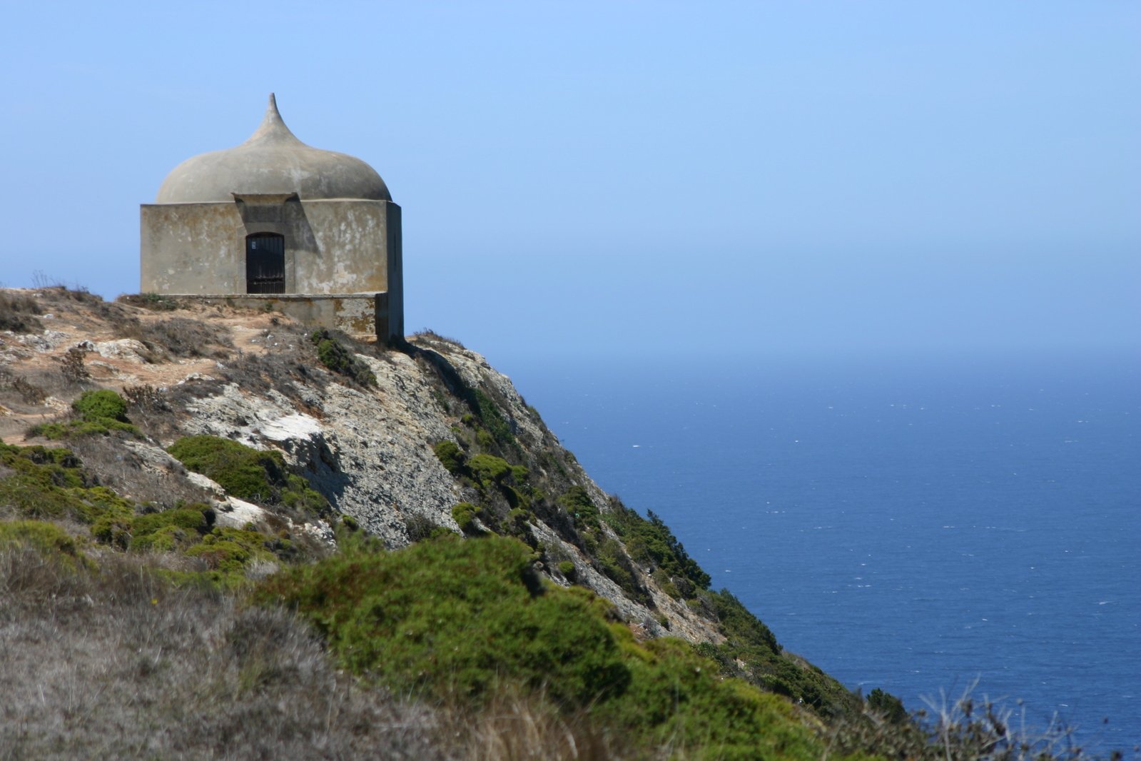 a dome sits on top of a hill by the ocean