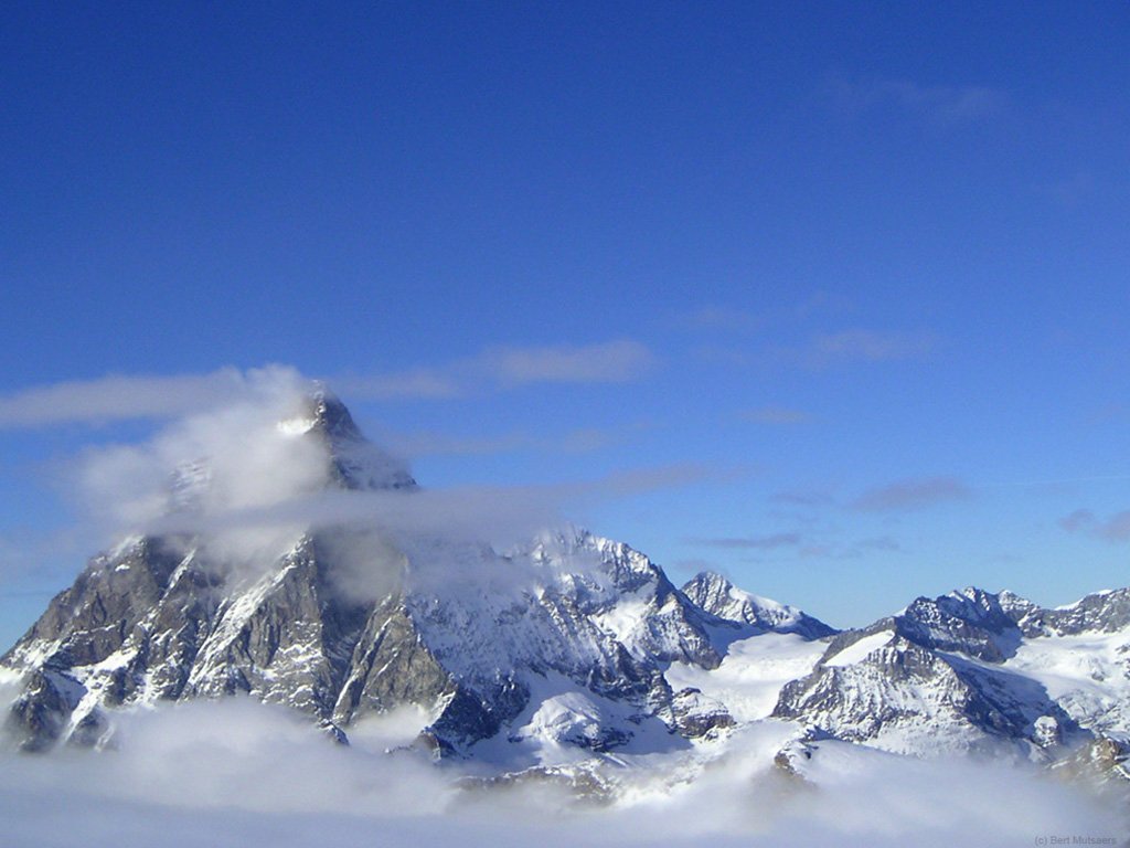 clouds are around the top of a mountain peak