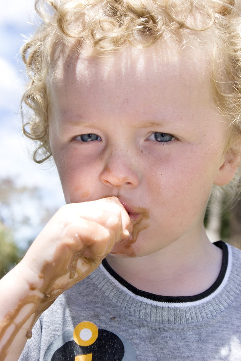 a close up of a child holding soing to his mouth