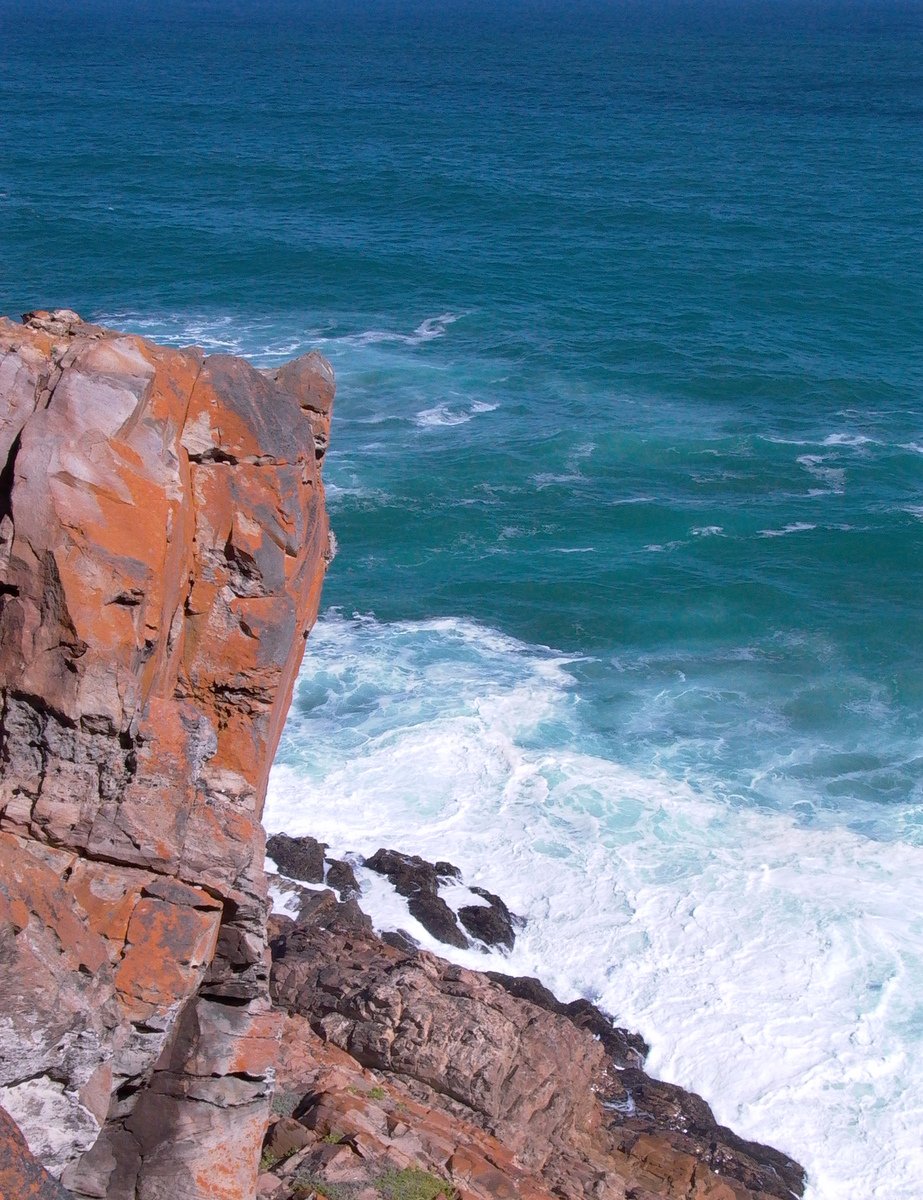 two people standing on rocks near the ocean