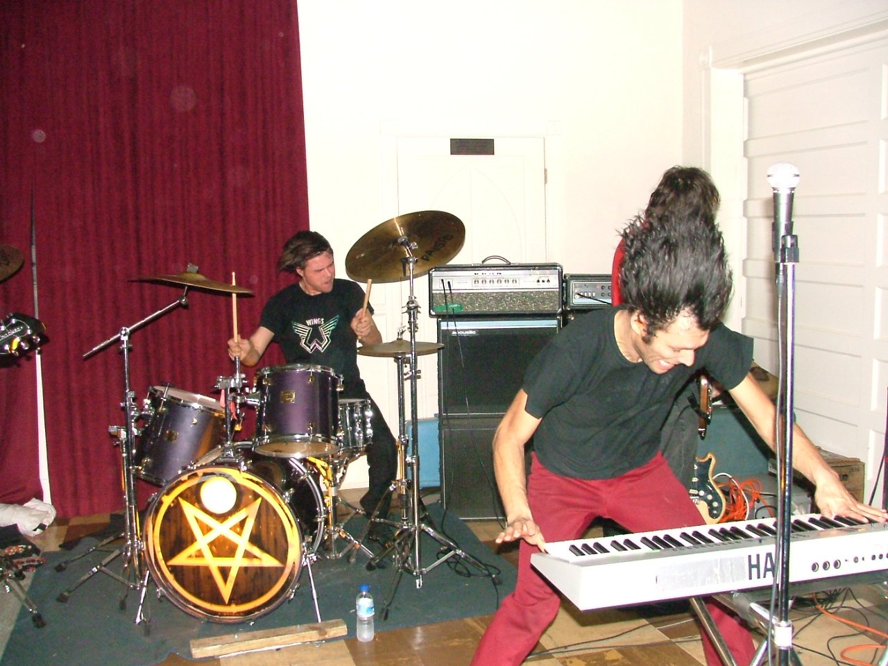 band playing instruments in an empty room with red curtains