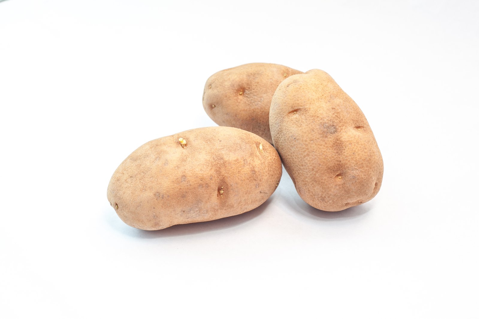 three sweet potatoes on a white surface