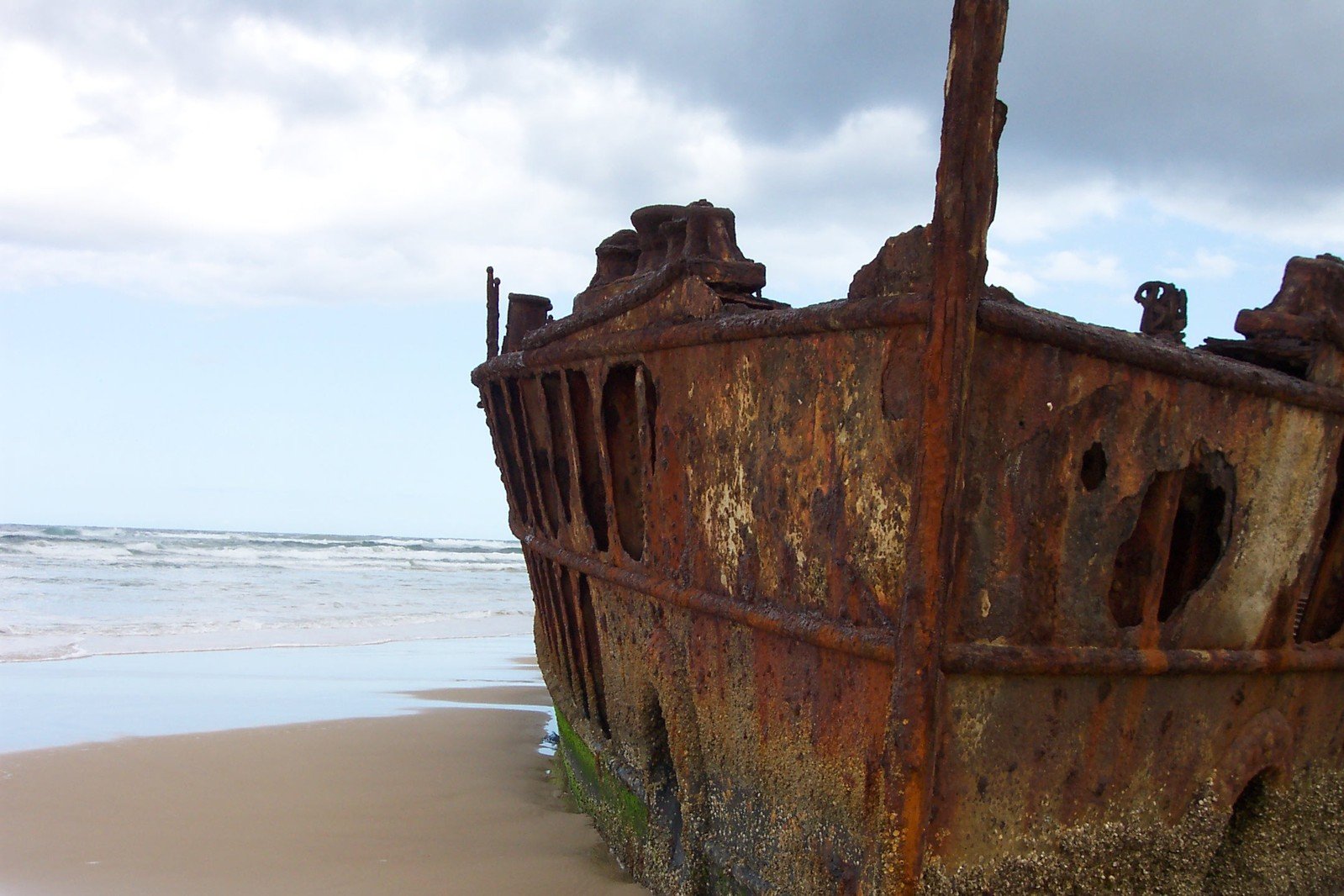 an old ship sits at the edge of the water