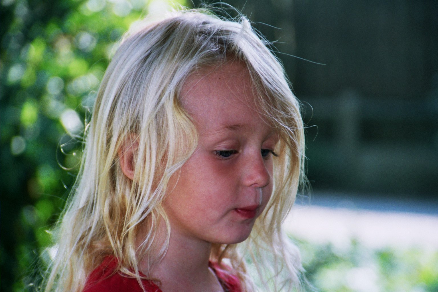 a young blonde girl is eating an orange outside