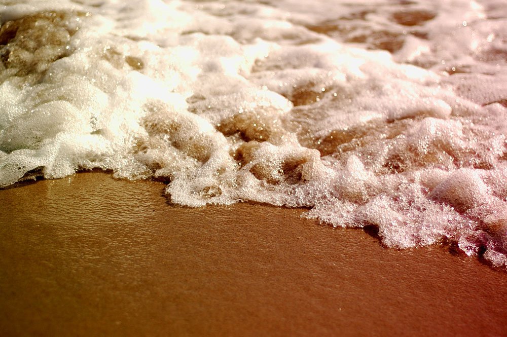 a sandy beach with some white foam on it