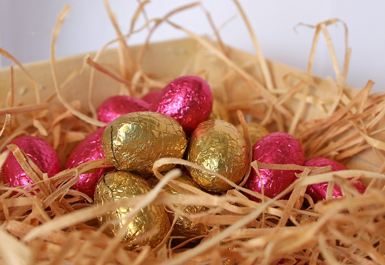a nest filled with gold and pink foil eggs