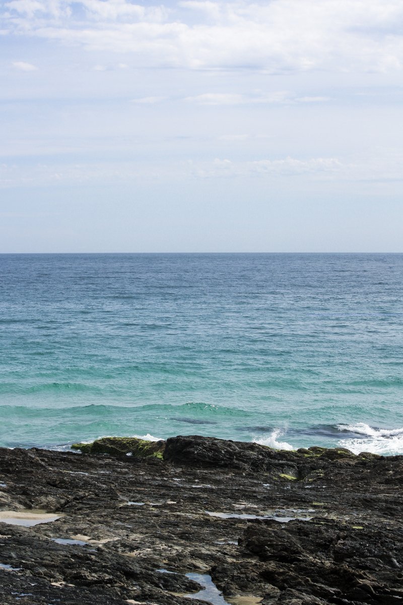 a lone person on a rocky beach in front of the ocean