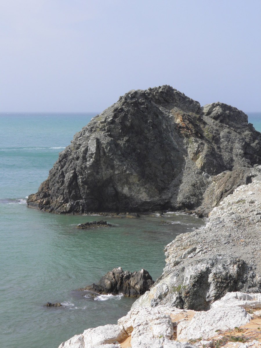 rocks are by the ocean and one is standing on a rock