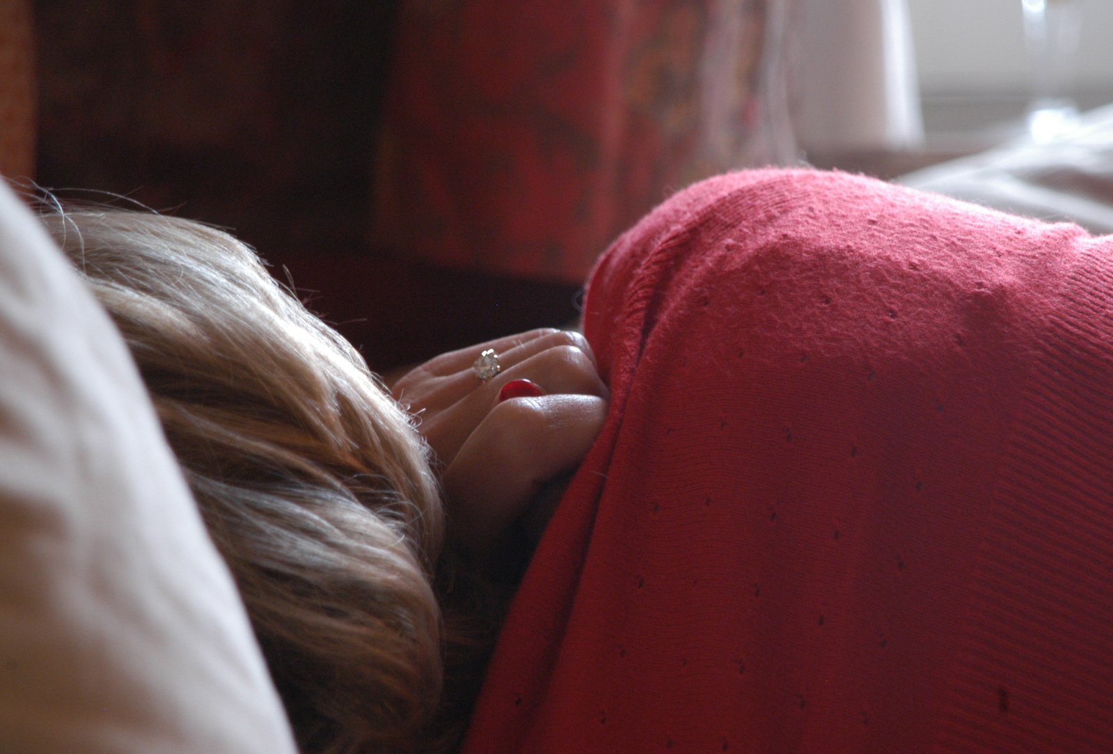 a girl in red blanket covering head with hand