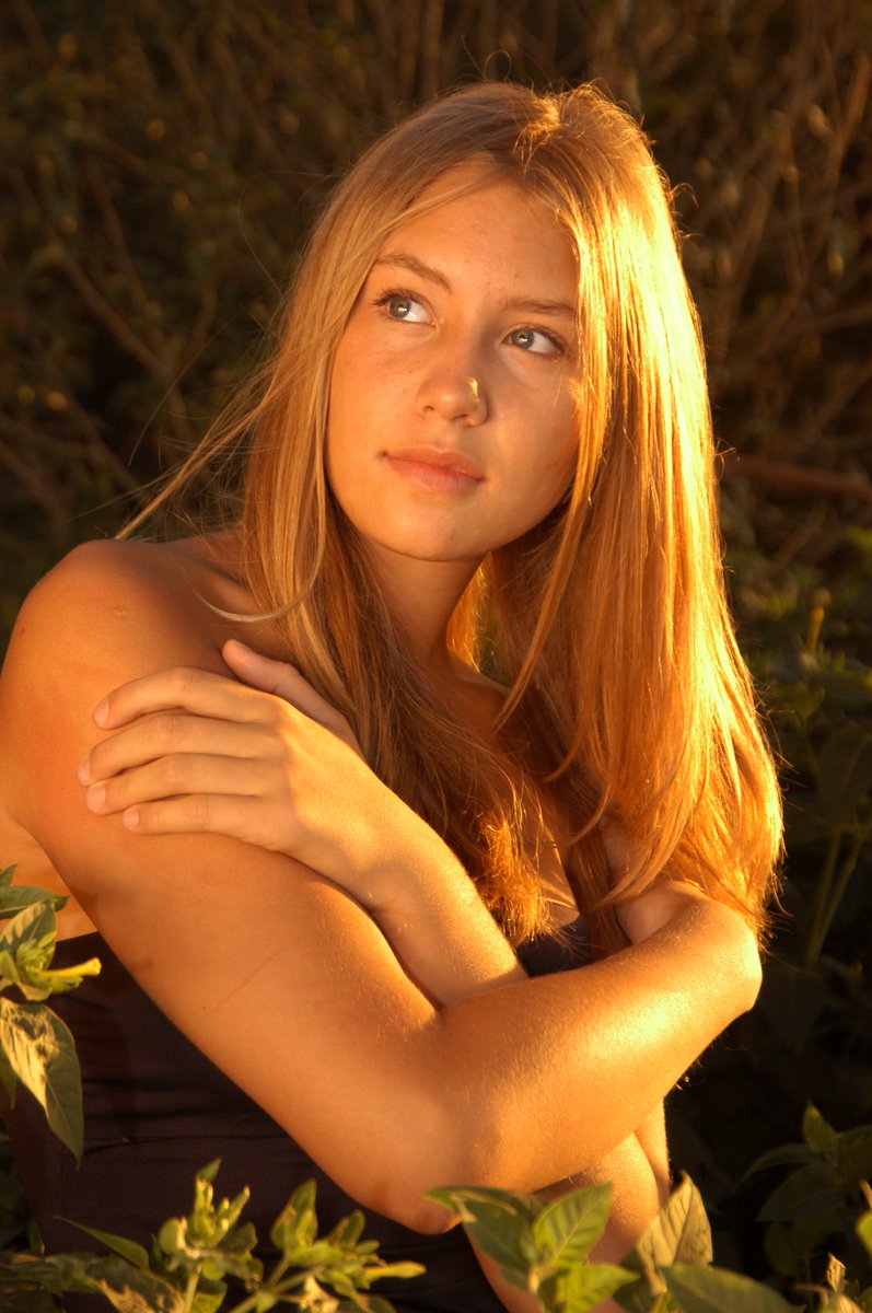 a young woman is posing in the sunlight