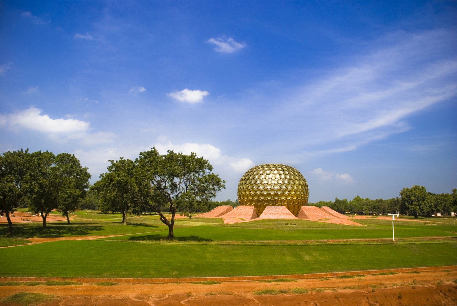 an outdoor golf course with large sphere shaped structure on one side and trees in the other