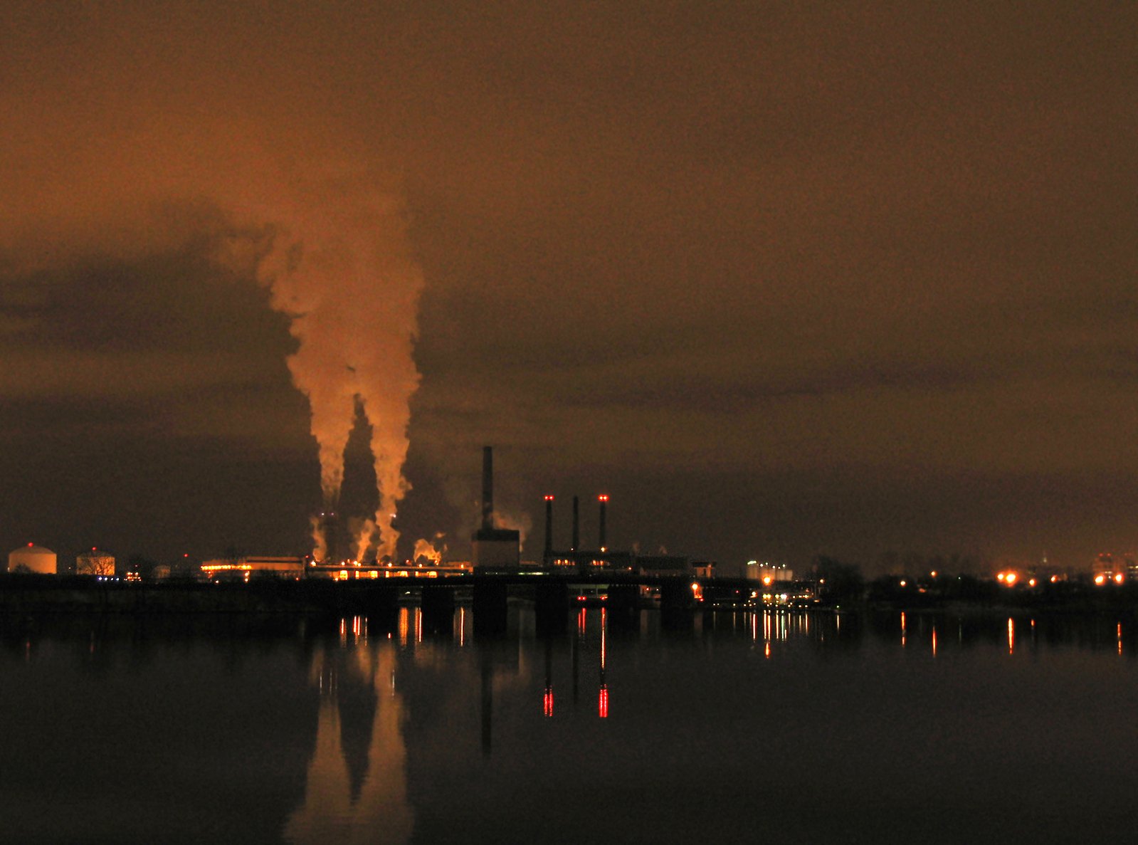 smoke pouring out of chimneys next to the city