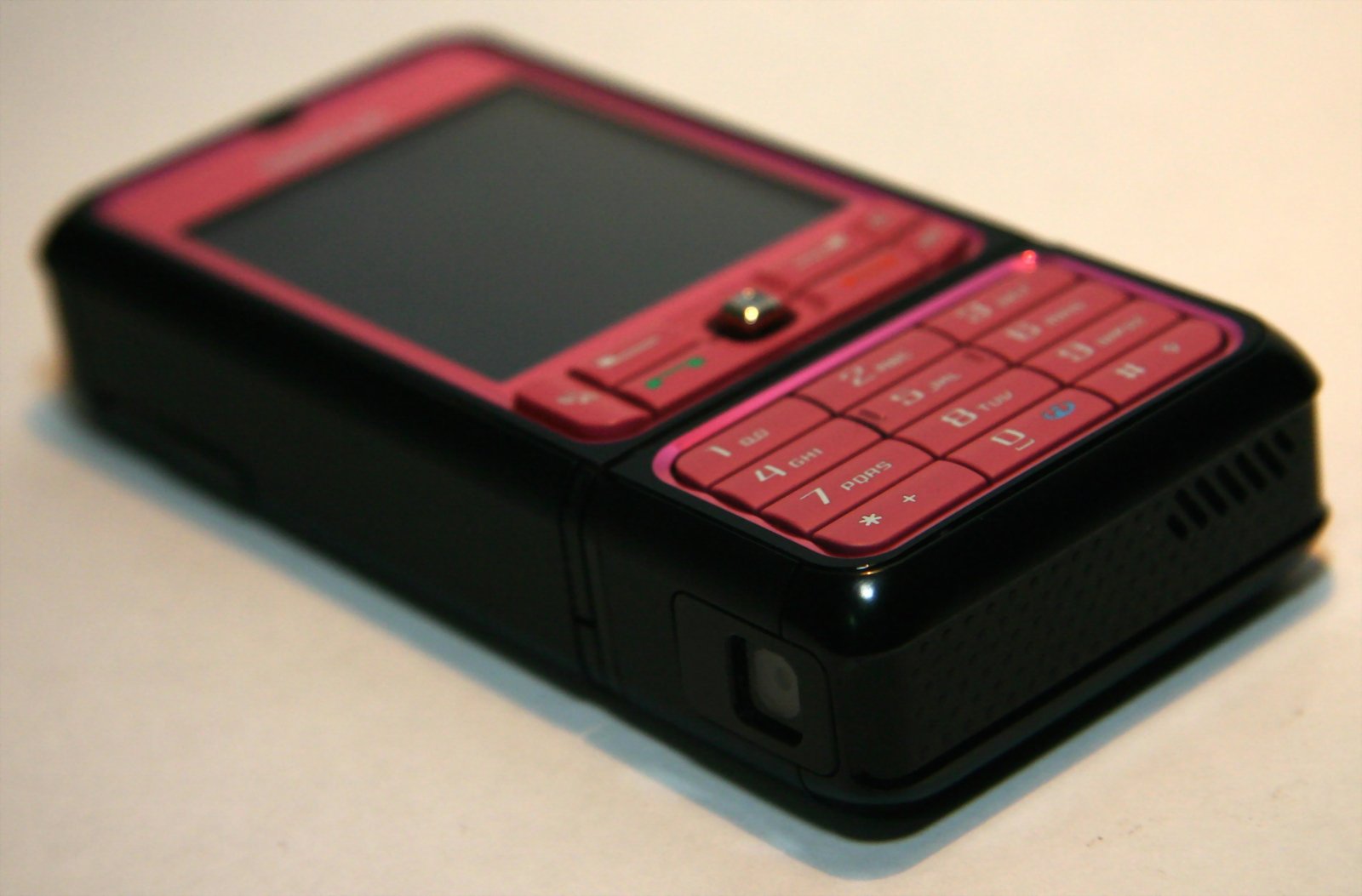 a red and black cell phone laying on top of a white table