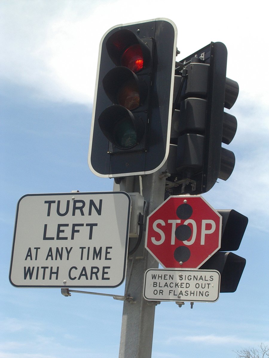 the street sign has a red stop light on it