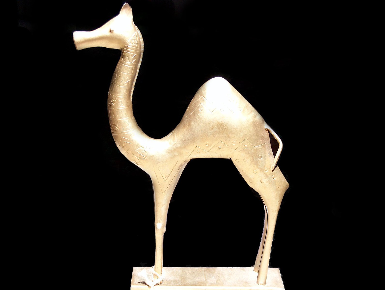 a statue of a gold giraffe sitting on a block