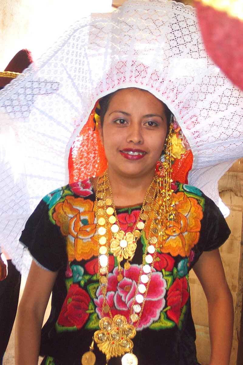 the woman is wearing very colorful jewelry and a large white parasol
