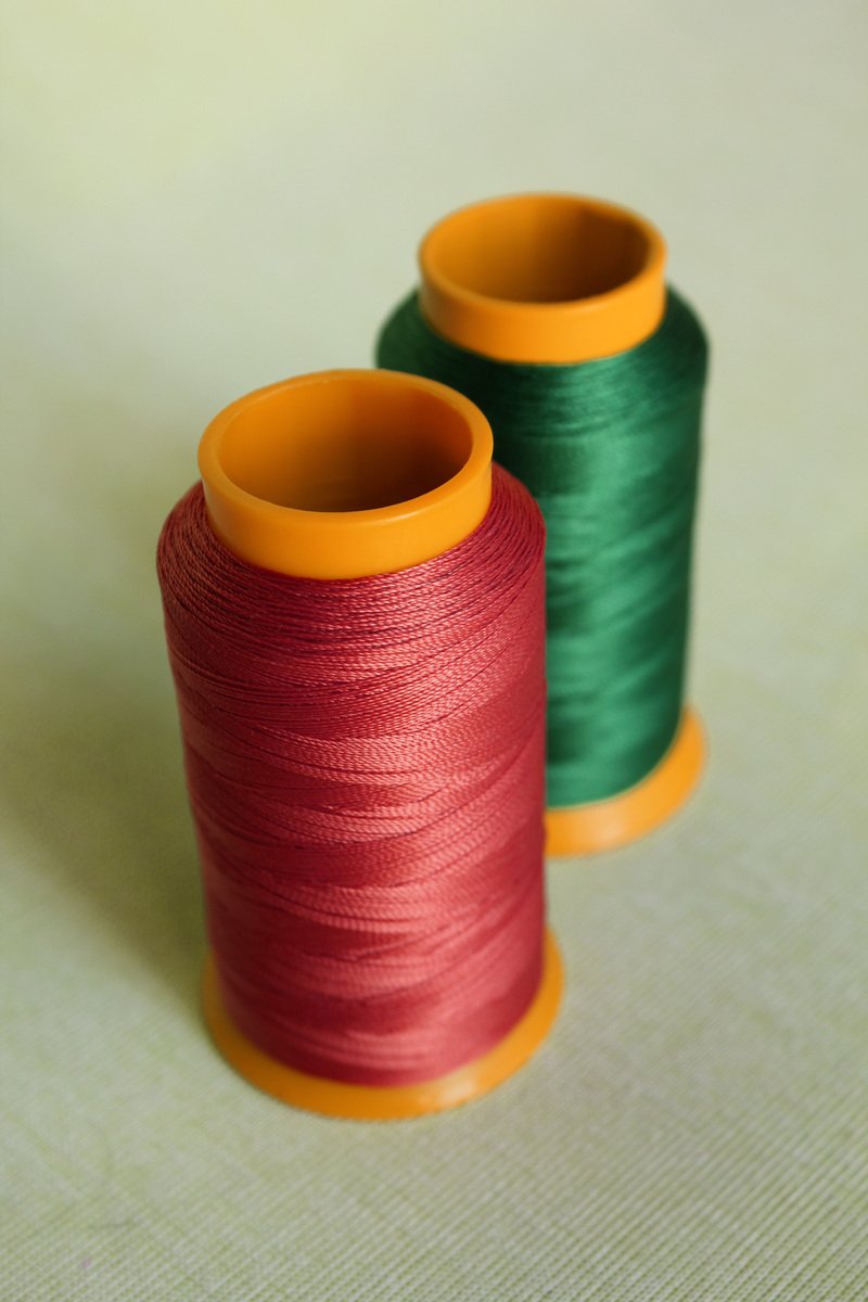 two spools of thread with colored cotton next to each other