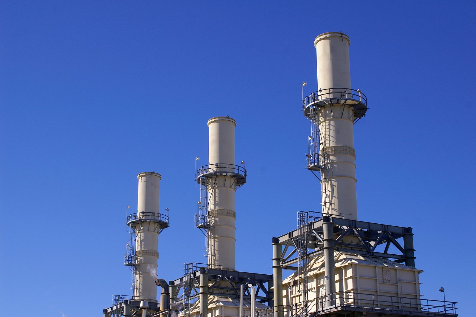 some smokestacks and pipes near a blue sky