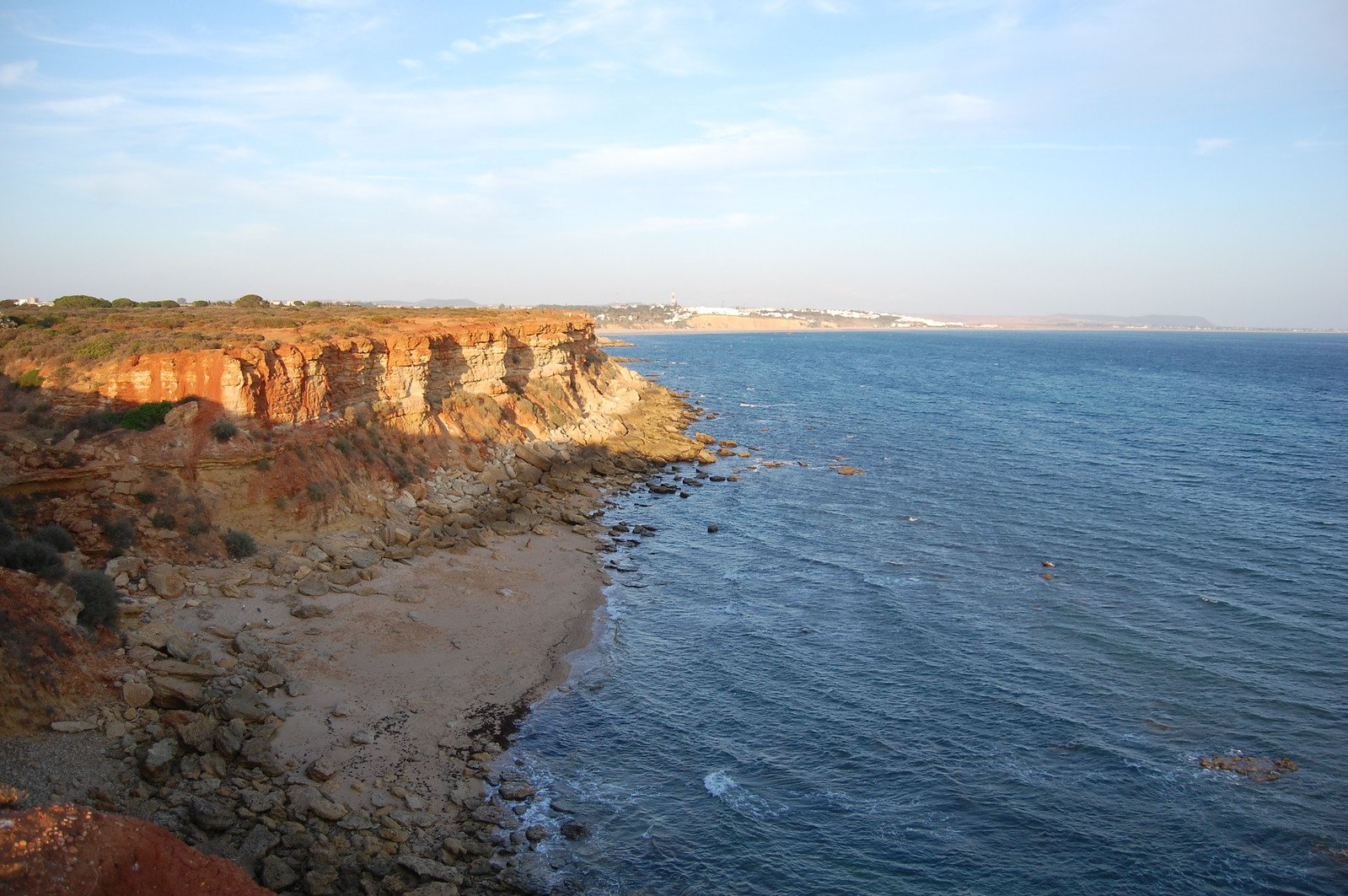 a cliff along the ocean next to a beach