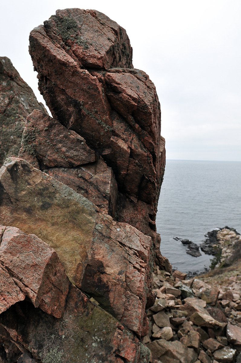 a big rock out by the ocean with lots of rocks on it