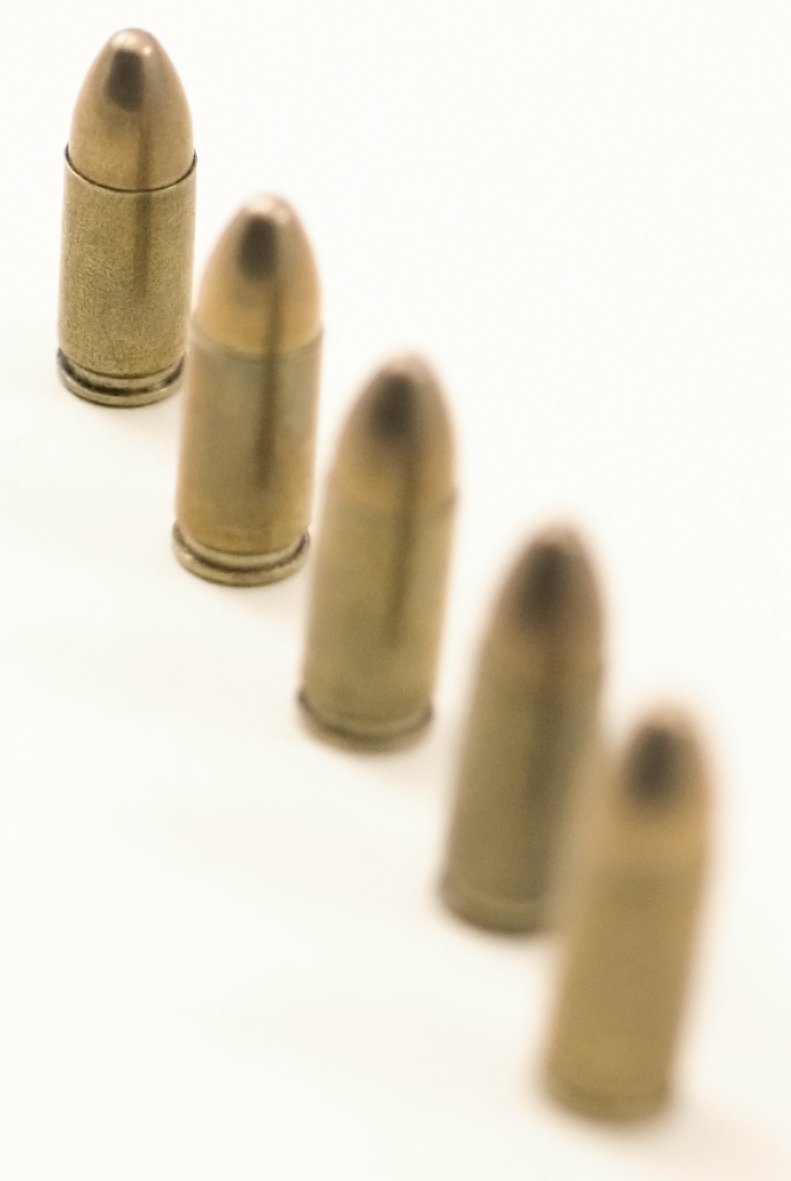five bullet shells lined up with no tops