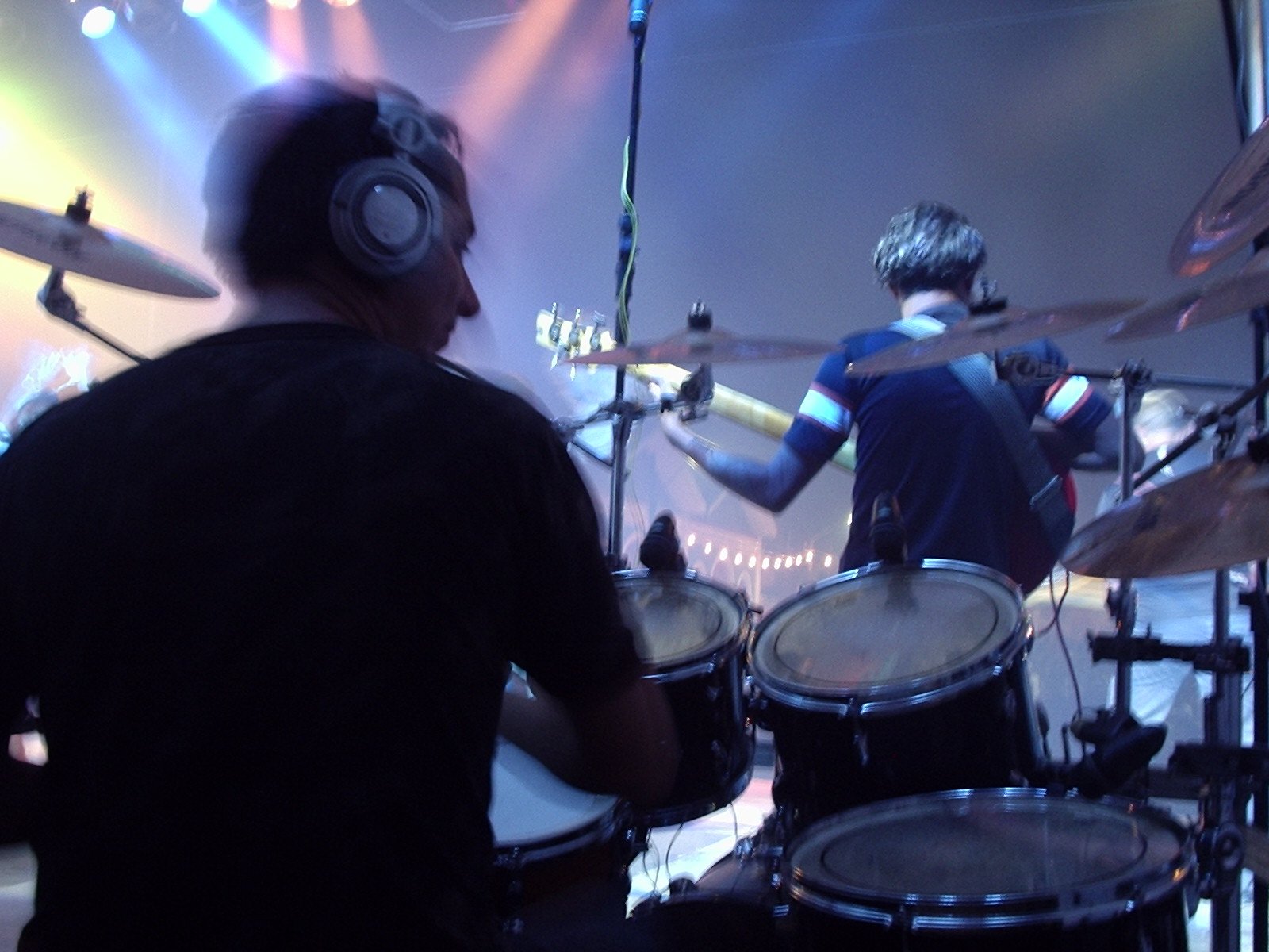 two guys playing drums on stage with headphones