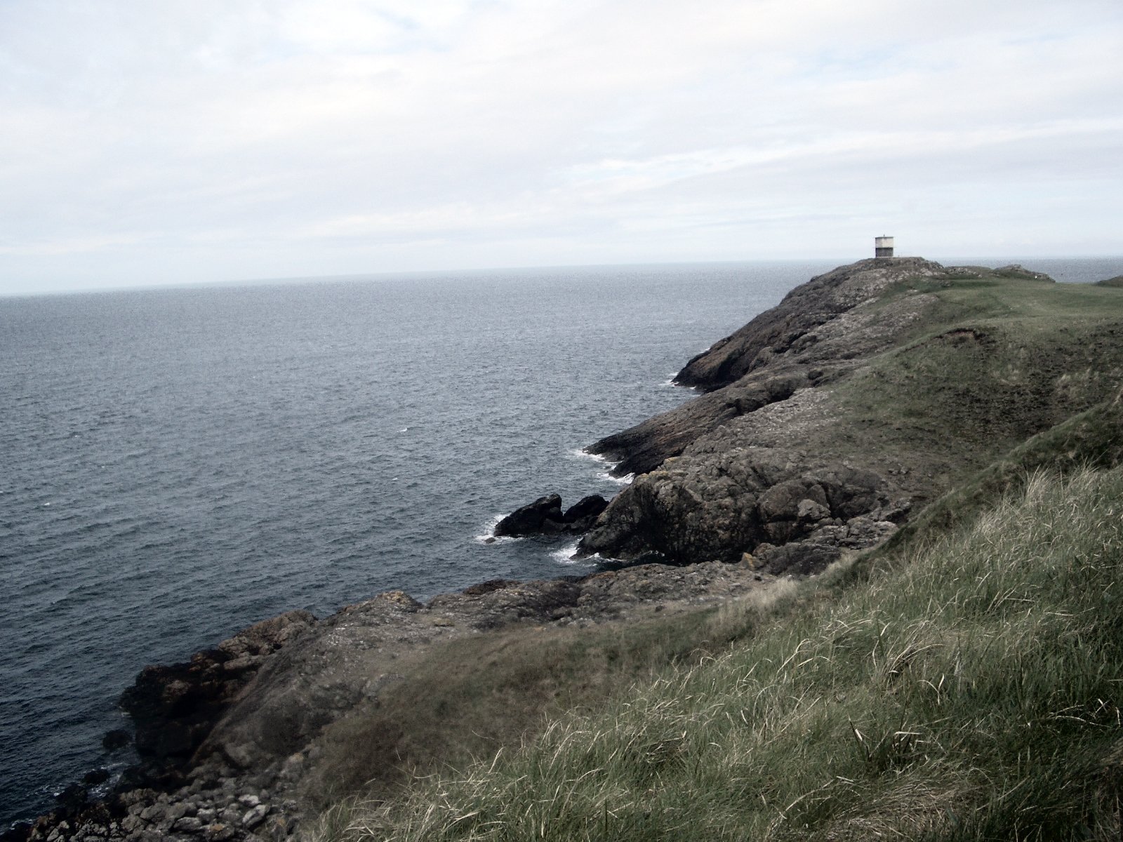 lighthouse with a person sitting at the end on top of it