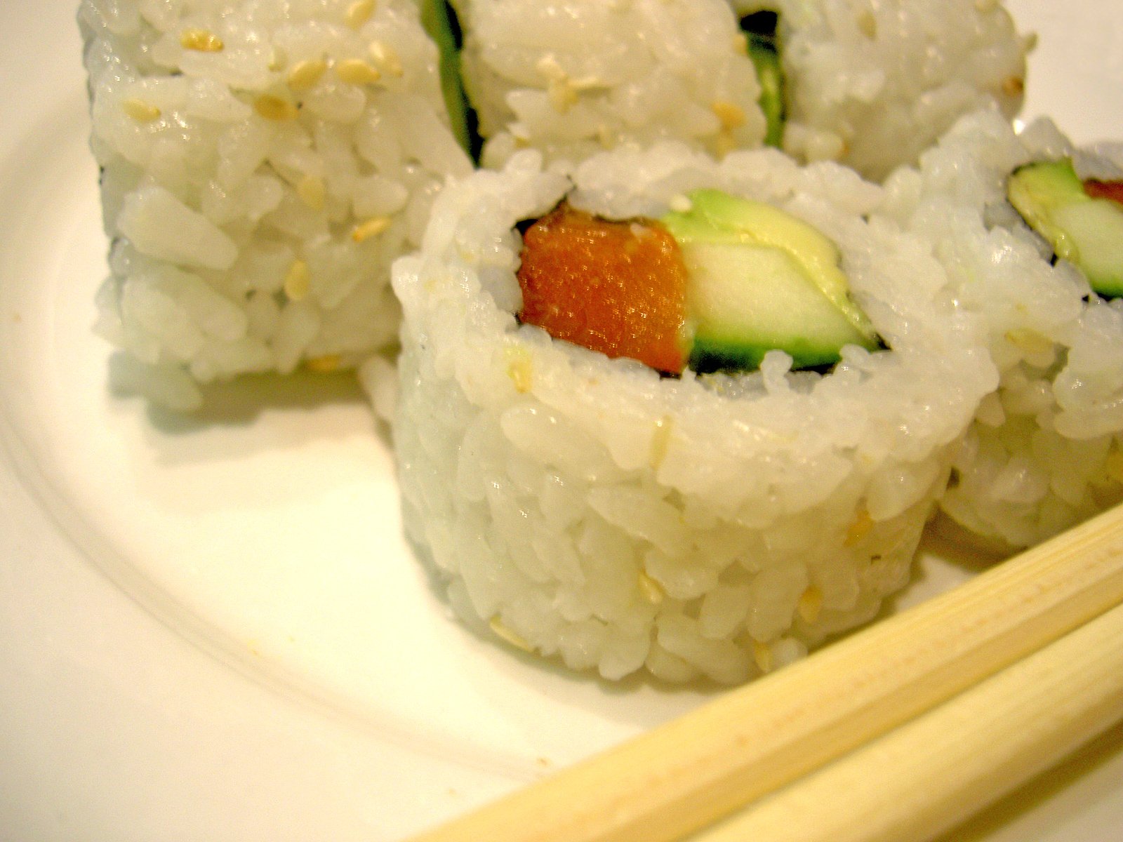 three rolls on top of white rice with chopsticks