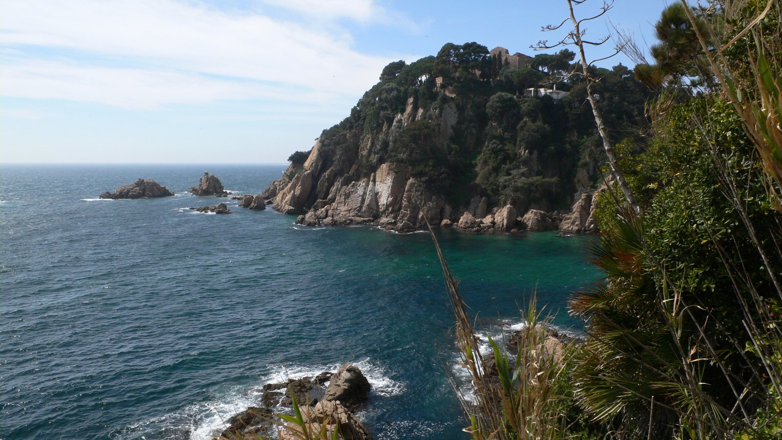 a rock cliff on the sea with the view of a house on it