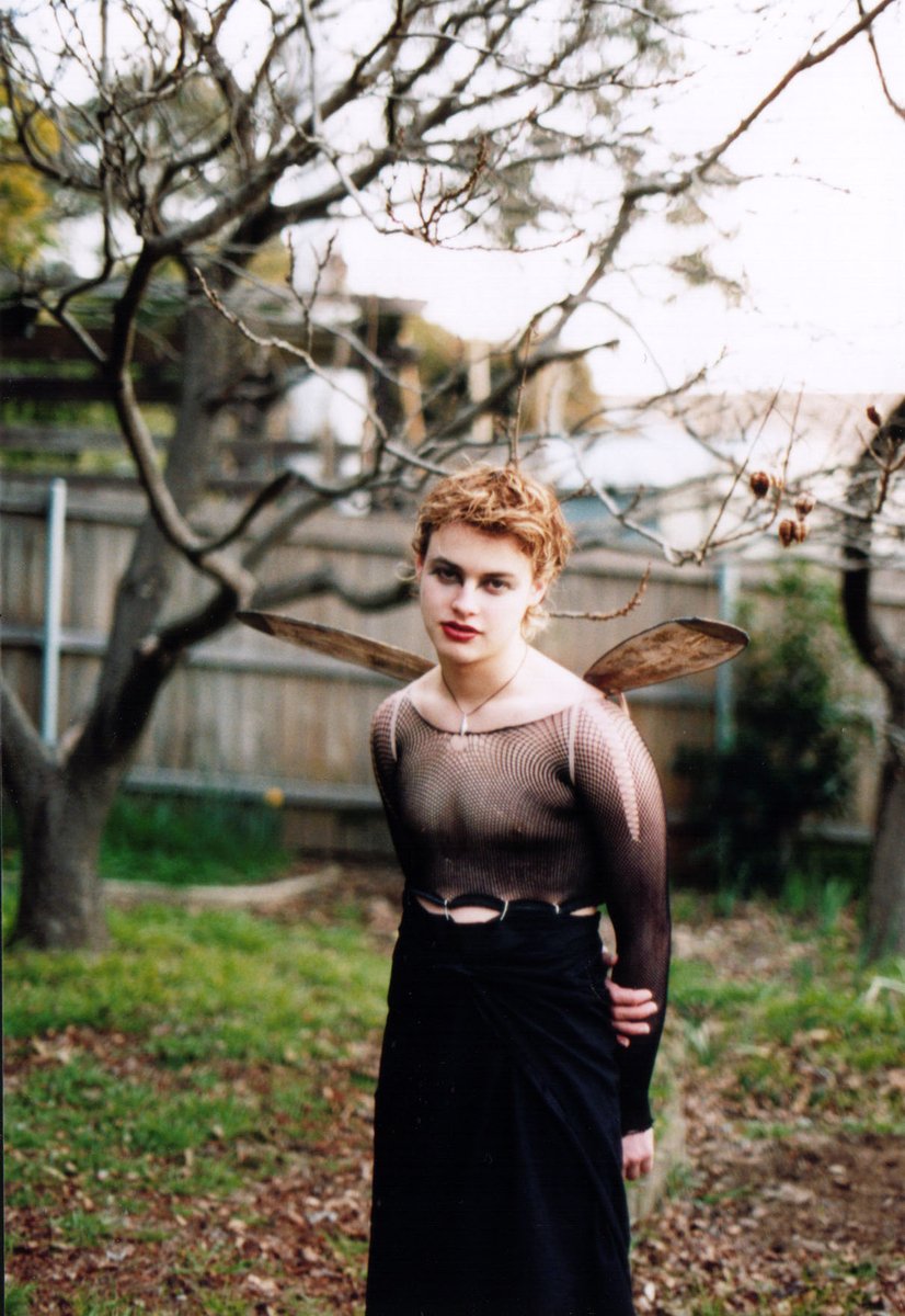 a woman with wings poses in the middle of a yard