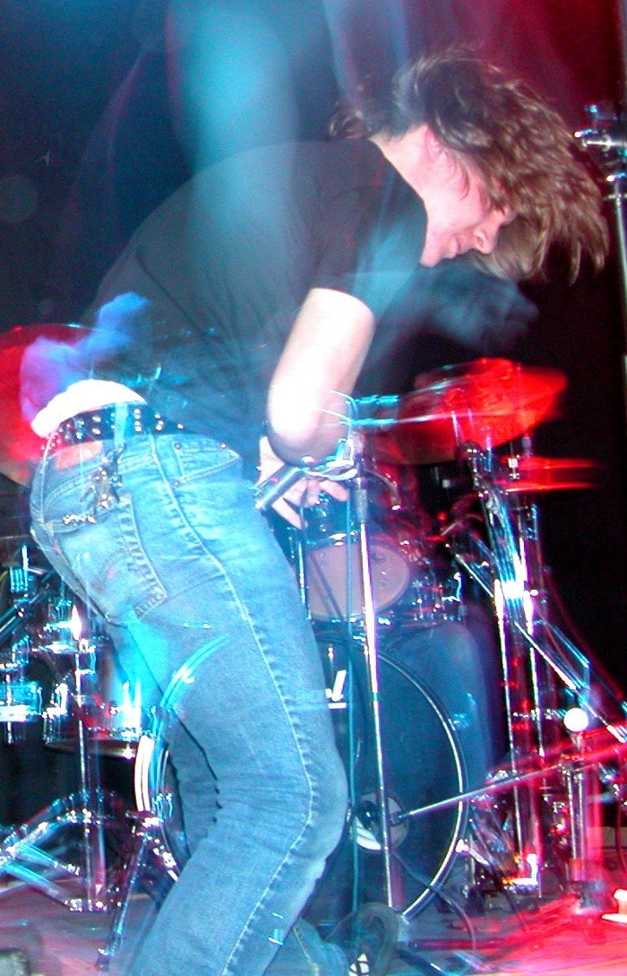 a guy in black shirt with a microphone and drums