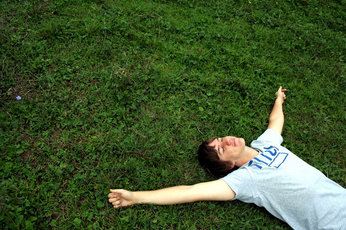 a boy is laying in the grass playing with a yellow frisbee