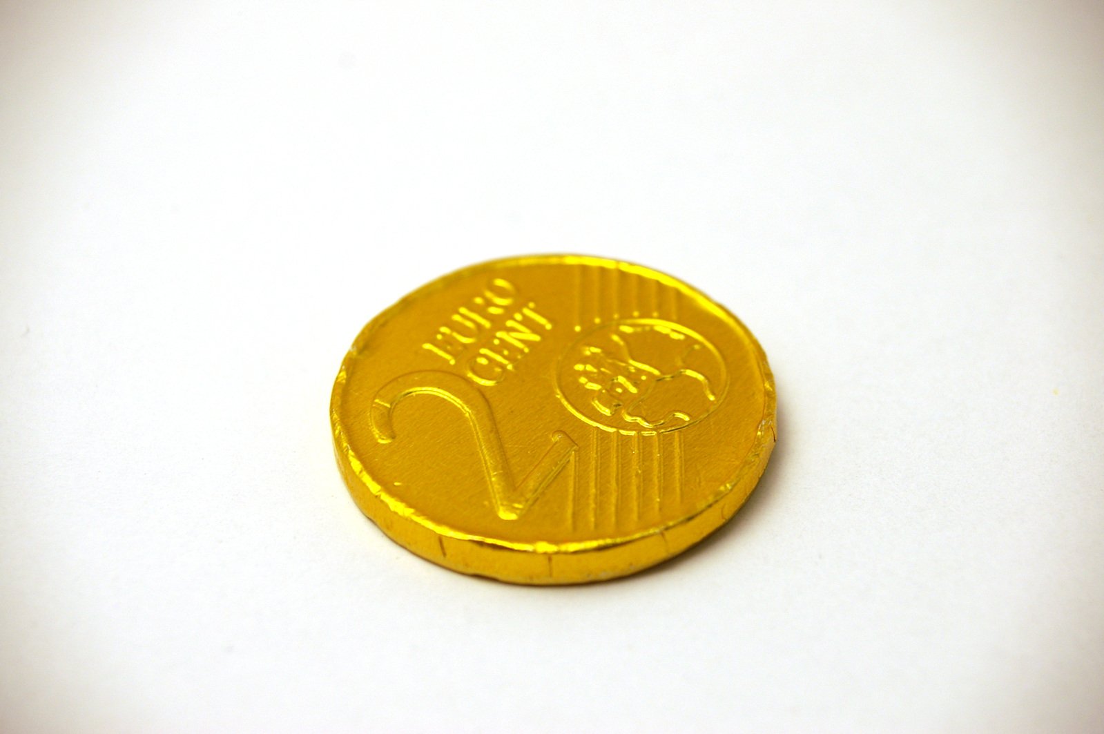 a round golden token coin sitting on a white surface