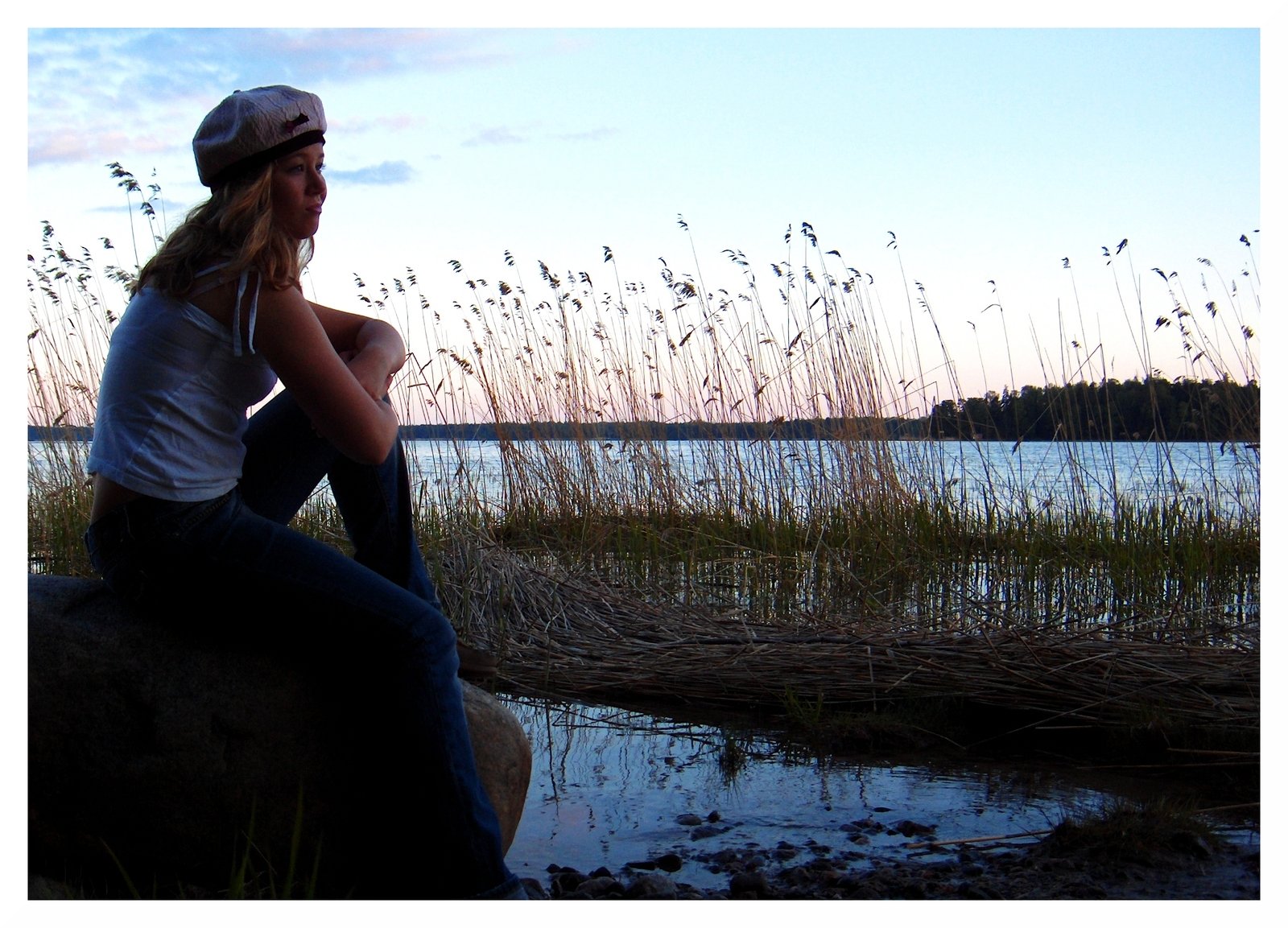 a woman wearing a hat sitting on a rock
