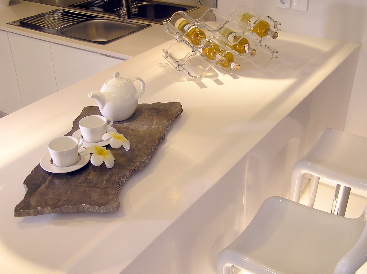 three glass tea kettles and three white cups are sitting on a countertop