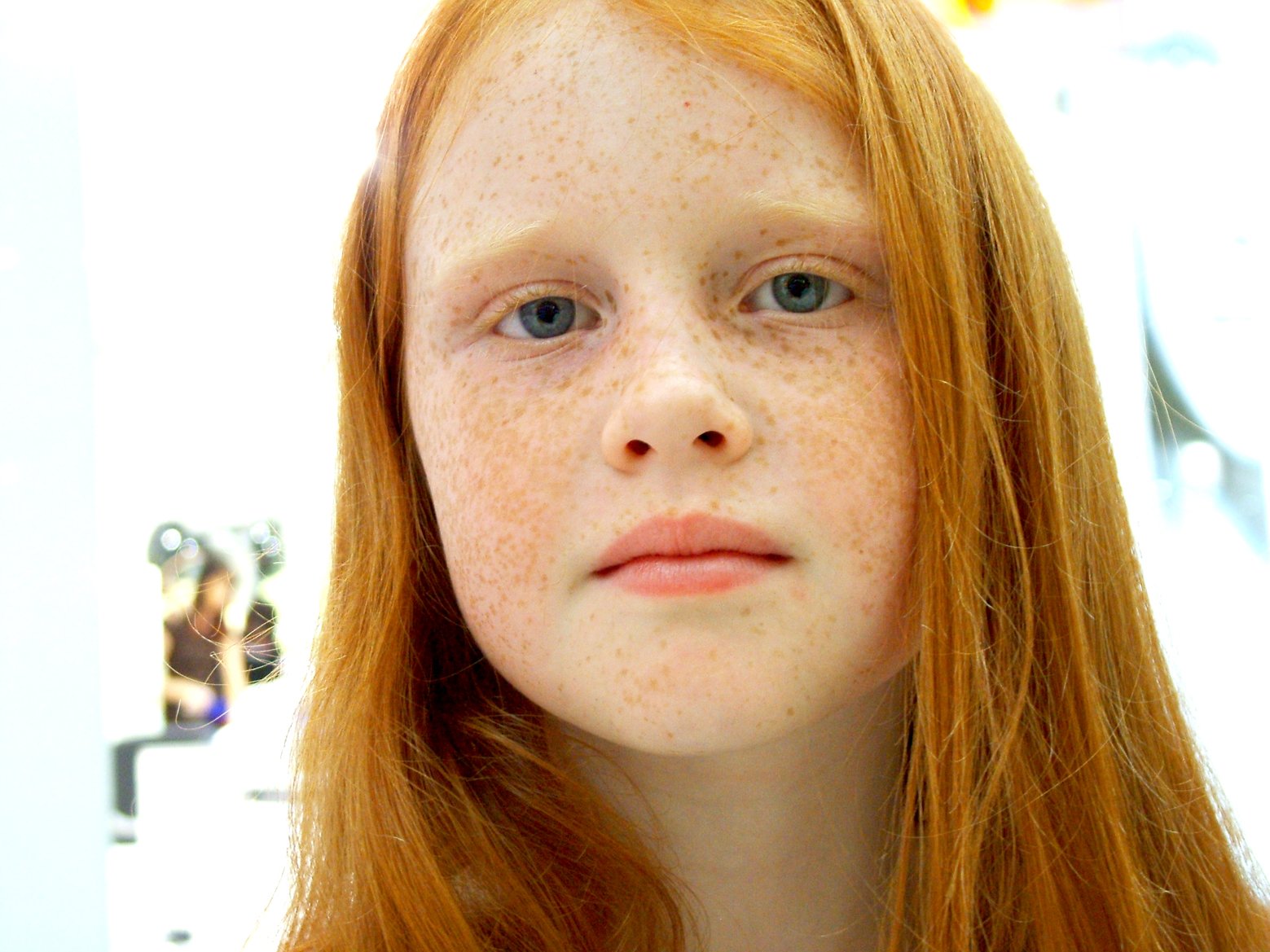 a woman with freckles on her face looking at the camera