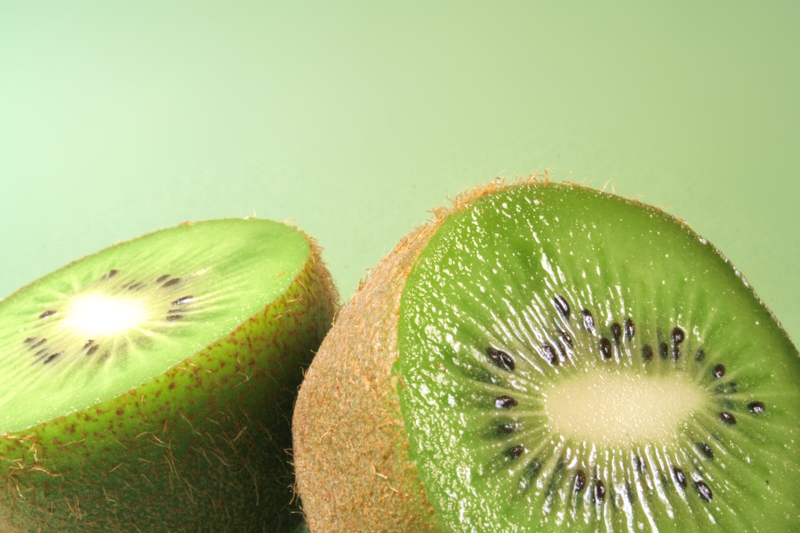 two kiwi slices are arranged in a pattern on a green surface