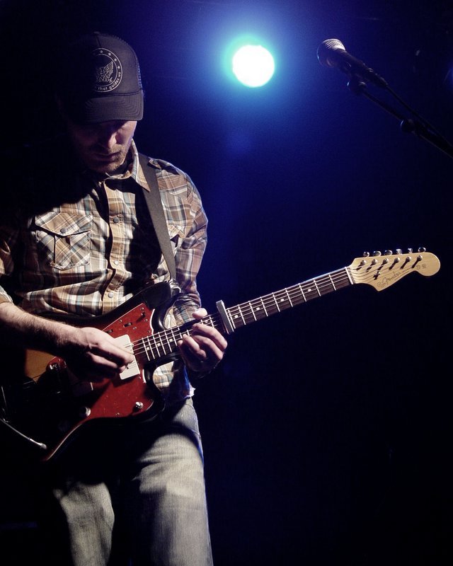 a man plays a guitar on stage at the concert