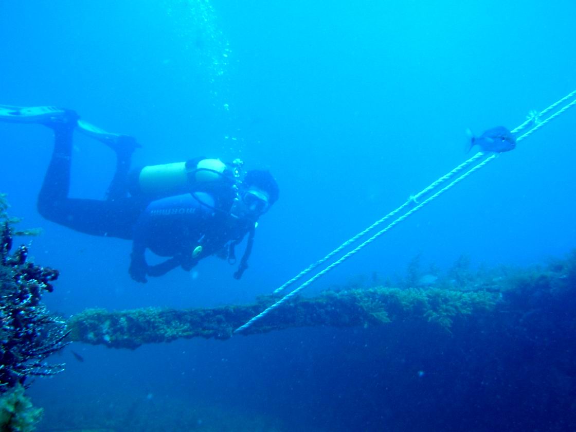 a man diving in the ocean near a plank